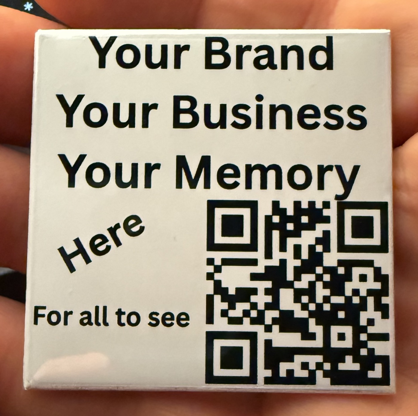 A hand holding a 2-inch square magnet reading 'Your Brand, Your Business, Your Memory' with a scannable QR code.