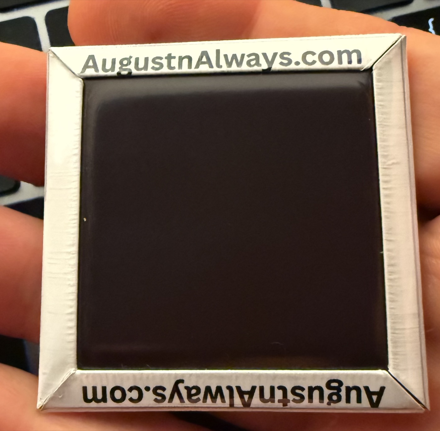 The finished back of a hand-pressed 2-inch magnet with a clean folded border.